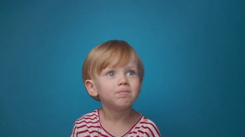 Portrait handsome baby looks sick on blue background, baby upset Stock Footage