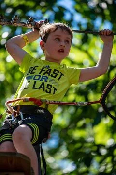 Portrait of a handsome boy on a rope park among trees. Children summer act... Stock Photos
