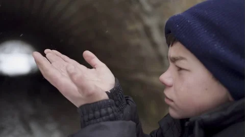 Portrait of a handsome boy in winter clothes catching snowflakes Stock Footage 72782292