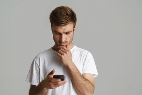 Portrait of handsome brooding man thinking and using mobile phone Stock Photos