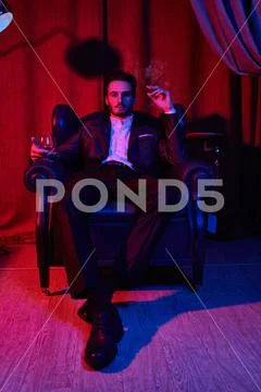 Portrait of a handsome brunet man sitting with a wine glass and smoking a cig Stock Photos