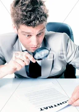 Portrait of a handsome businessman looking at a contract with magnifying glas Stock Photos