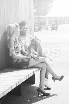 Portrait of handsome couple in casual clothing with sunglasses sitting on woo Stock Photos