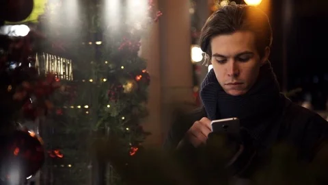 Portrait of handsome guy using smartphone on a busy city street in evening Stock Footage 83630797