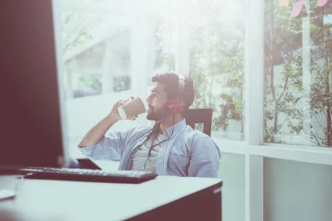 Portrait of handsome man with beard drinking coffee and listening to music on Stock Photos