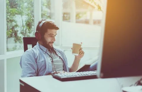Portrait of handsome man with beard drinking hot coffee and listening to musi Stock Photos