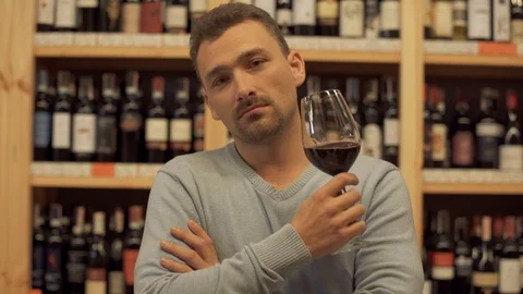 Portrait of handsome man drinking red wine. Man shakes his drink, raises wine Stock Footage 99386411