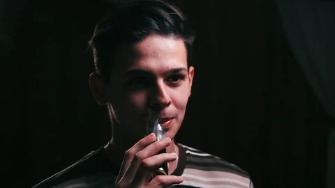 Portrait of handsome man with electronic cigarette indoors at night Vidéo 99050686