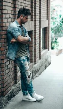 Portrait of handsome man leaning on brick wall, looking away to a side. Toned Stock Photos