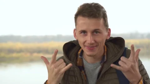 Portrait of handsome man looking at camera and showing cool, rock and roll sign Stock Footage 100887778