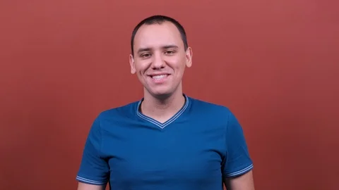 Portrait handsome man looking at camera smiling close up on red background 4K. Stock Footage 122764882