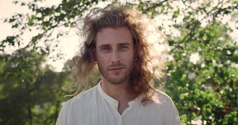 Portrait of handsome man looking to camera while wind blowing his long blond Stock Footage 144818195
