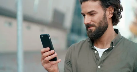 Portrait of Handsome Man looking at Screen of his Smartphone, standing in the Stock-Footage 125146689