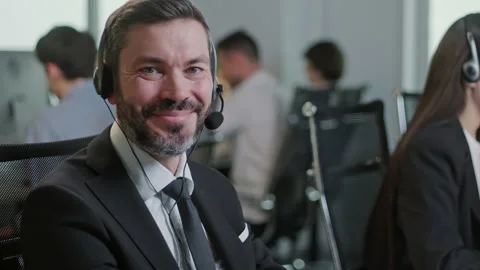 Portrait of Handsome Man Operator Look at Camera Smie Taking Calls Smile in Call Stock Footage 168729411