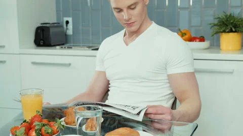 Portrait of handsome man reading newspaper at breakfast table. Vidéo 86715705