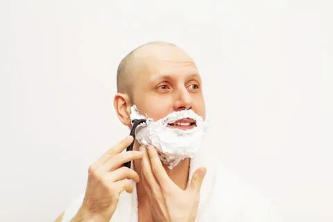 Portrait of handsome man shaving using a razor and looking away Stock Photos