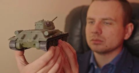 Portrait of handsome man with small model prototype  of tank.He carefully spinin Stock Footage 118823525