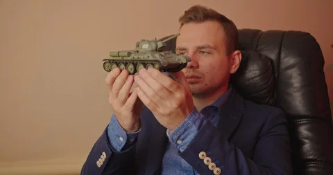 Portrait of handsome man with small model prototype  of tank.He carefully spinin Stock Footage 118825209