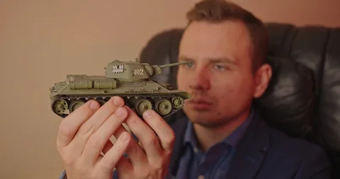 Portrait of handsome man with small model prototype  of tank.He carefully spinin Stock Footage 118826529