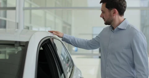 Portrait of handsome man touching new car in showroom. Concept of car shopping Stock Footage 307698398