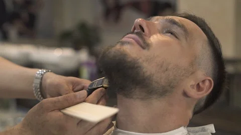 Portrait handsome man while shaving beard with electric razor in barber salon Stock Footage 94622118