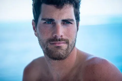 Portrait of handsome man with white teeth smile, shirtless surfer and blue oc Foto stock