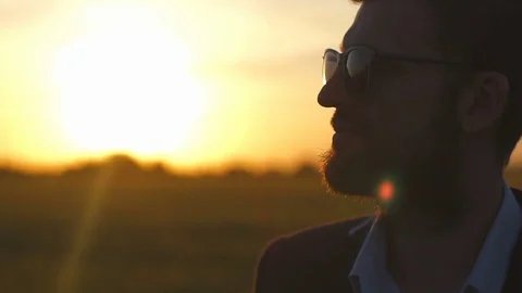 Portrait of a handsome man whos touching his chin sundown field slow motion Stock Footage 76470586