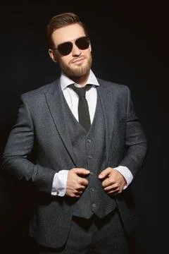 Portrait of a handsome smiling man wearing suit and sunglasses on a black bac Stock Photos