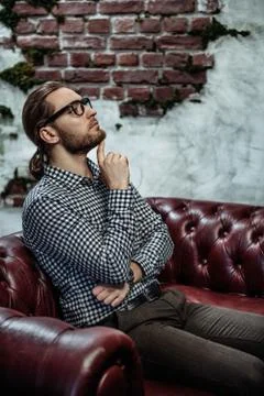 A portrait of a handsome stylish man sitting on the sofa. Fashion for men. In Stock Photos