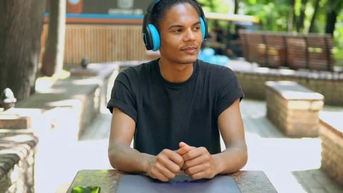 Portrait handsome trendy guy sitting in park listening music Stock Footage 114760140