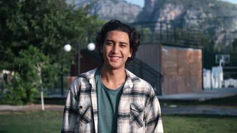 Portrait handsome young Arabic guy posing at summer sunny park with positive Видео 219958764