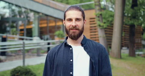 Portrait of a handsome young bearded man smiling and looking at the camera. Posi Stock Footage 327550968