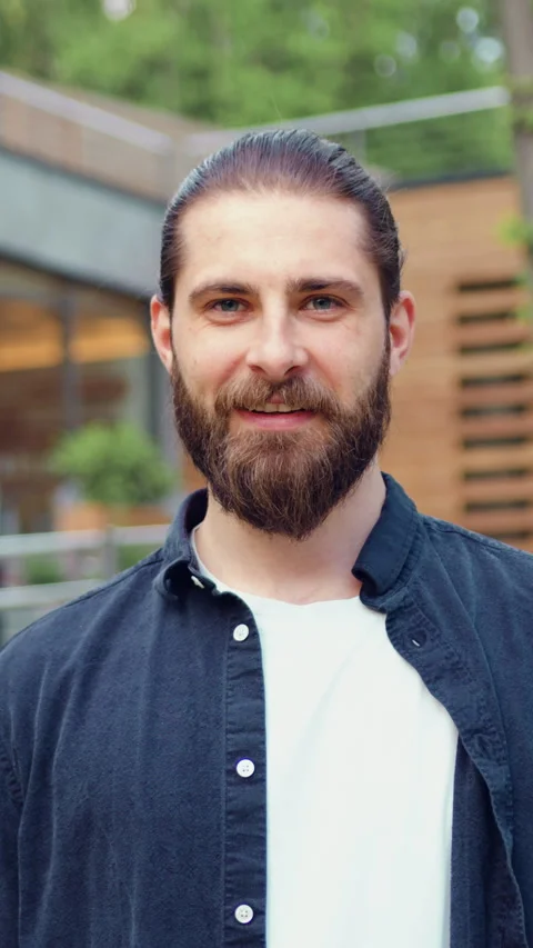Portrait of a handsome young bearded man smiling and looking at the camera. Posi Stock Footage 329054338