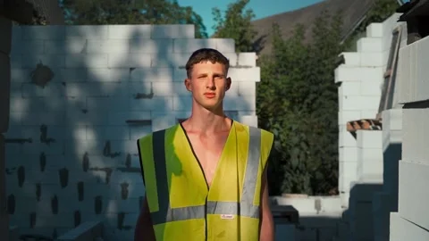 Portrait of a handsome young builder at a construction site in the evening sun Stock Footage