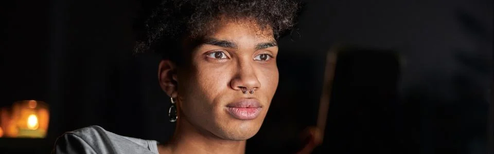Portrait of handsome young guy using smartphone at night, sitting in dark room Stock Photos