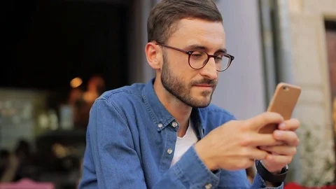 A portrait of a handsome young man communicating via mobile phone. At the cafe Stock Footage 81050506