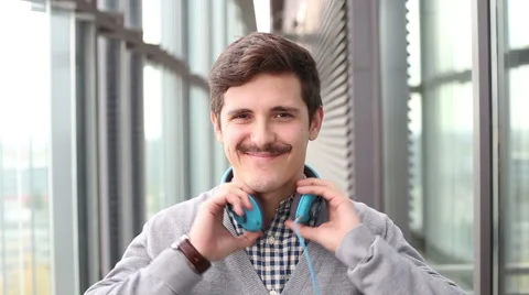 Portrait of handsome young man puts on headphones and listens to music Stock Footage 59542672