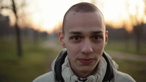 Portrait of handsome young man standing in the park in the evening in a winter Stock Footage 121061877