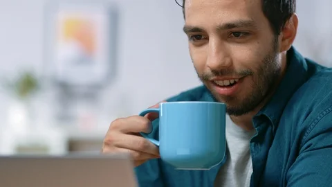 Portrait of Handsome Young Man Using Laptop Computer at Home, Watching and Laugh Video stock 97518035