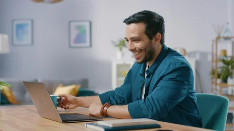 Portrait of Handsome Young Man Using Laptop Computer at Home, Watching and Laugh Video stock 97518969