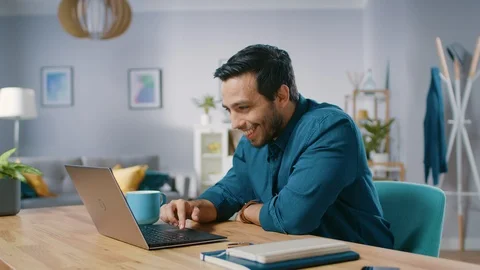 Portrait of Handsome Young Man Using Laptop Computer at Home, Watching and Laugh Video stock 97519191