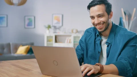 Portrait of Handsome Young Man Using Laptop Computer at Home, Watching and Laugh Video stock 97520537