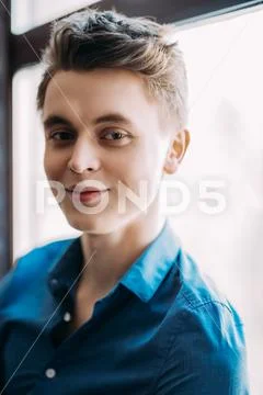 A portrait of a handsome young man wearing a blue shirt and posing indoor. Me Stock Photos