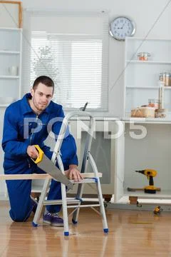 Portrait of a handyman cutting a wooden board Stock Photos