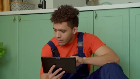 Portrait of handyman watching tutorial video to assemble DIY furniture Stock Footage 241131899