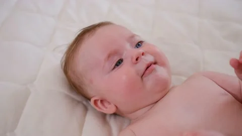 Portrait happy baby on the bed pulling his leg into his mouth, five months old. Stock Footage 203478337