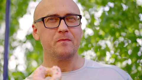 Portrait of a happy bald man bitting doughnut outdoor. Stock Footage 89978147