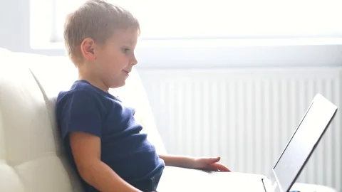 Portrait of happy boy playing with computer. Attractive kid with a laptop at Stock Footage 112251425