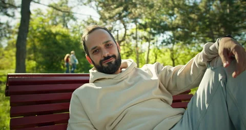 Portrait of a happy brunette guy with a beard in a White hoodie who sits on a Stock Footage 280612294