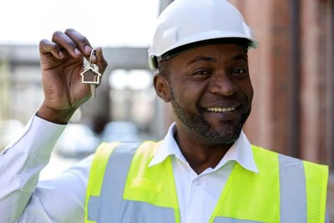 Portrait of happy construction engineer holding keys from new home. African Stock Photos